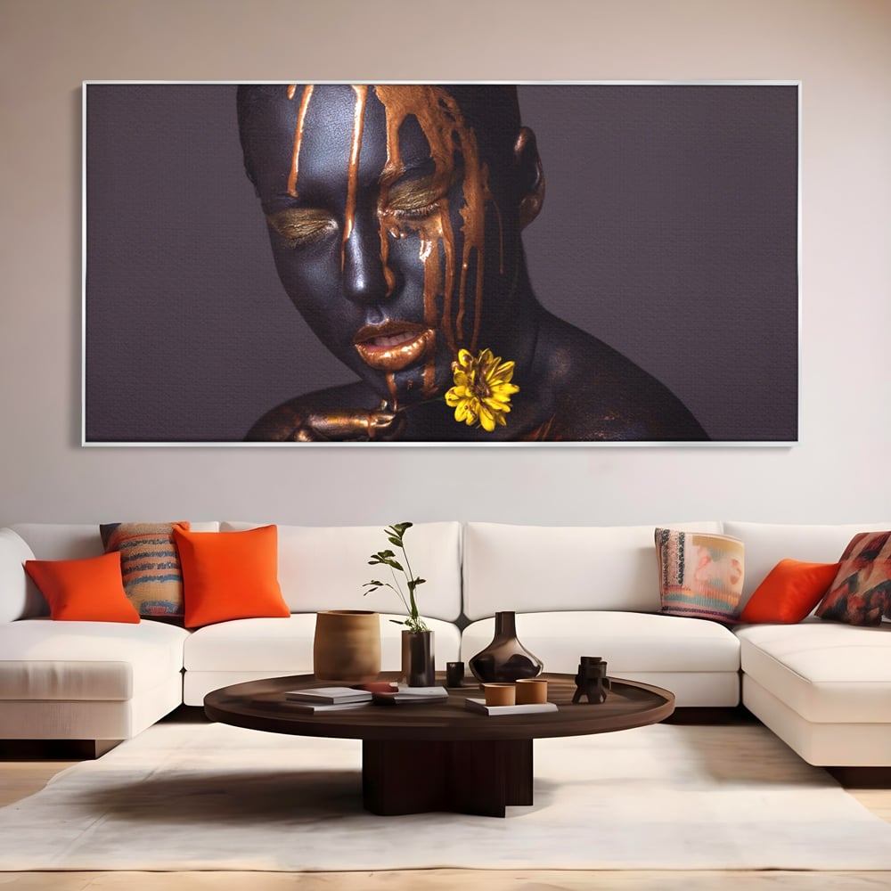 Tablou canvas cu tablou canvas cu femeie si vopsea aurie, in rama de aluminiu argintiu, pe perete intr-un living